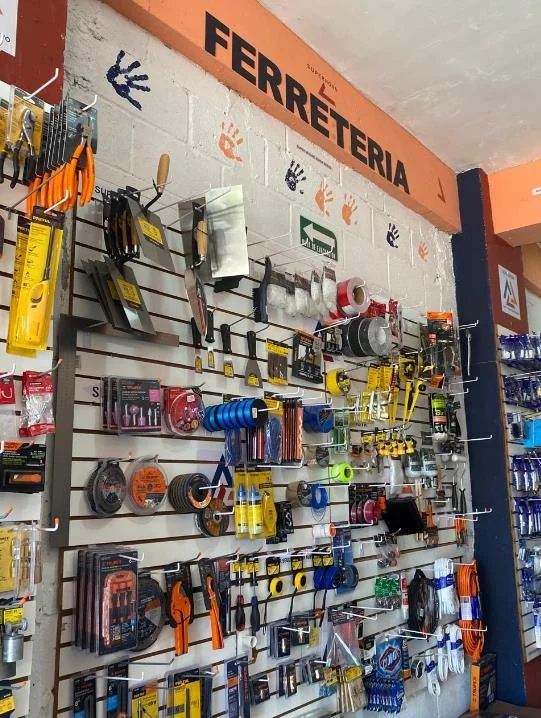 Muro de herramientas bajo letrero de ferretería en la tienda Supernova